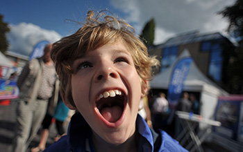 Kid at a mad science booth smiling with mouth open