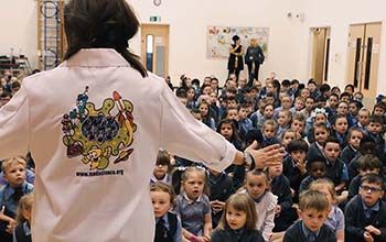 Mad Scientist at special event presenting to room full of children sitting on the floor