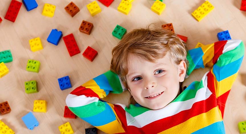 Boy lying on the floor in colorful striped shirt lying on Lego