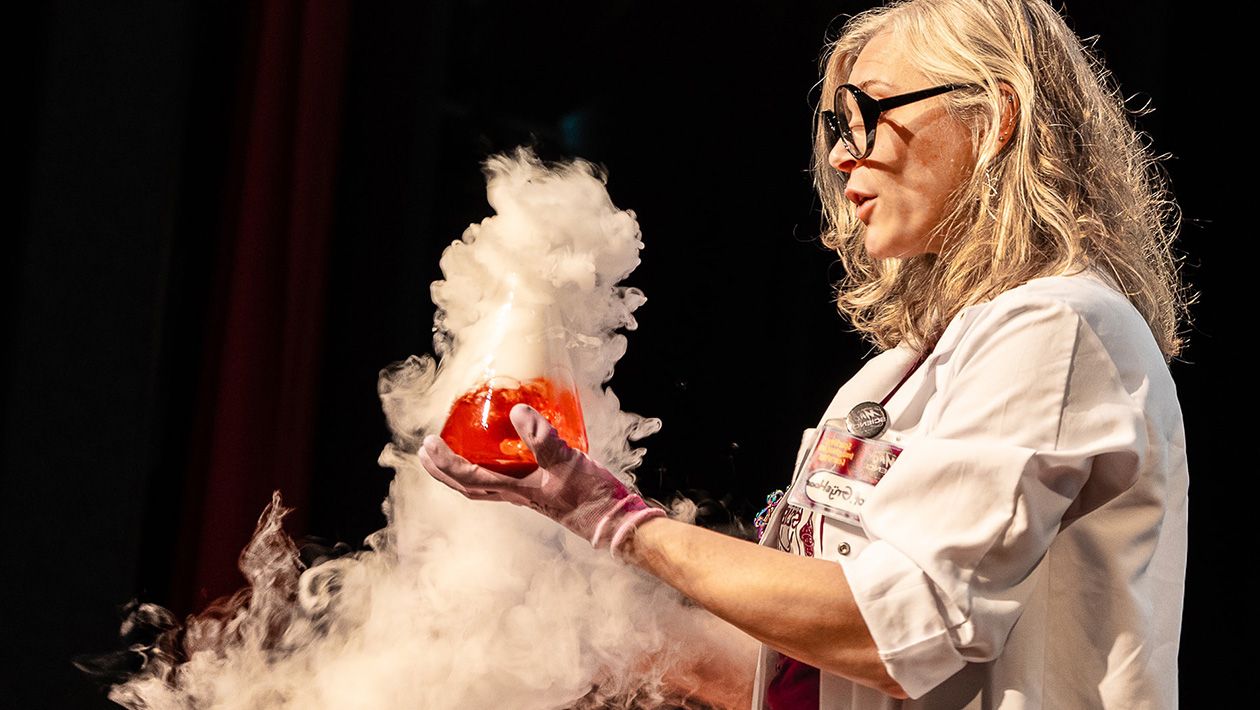 Mad scientist holding a beaker with a red liquid inside and smoke pouring out of it